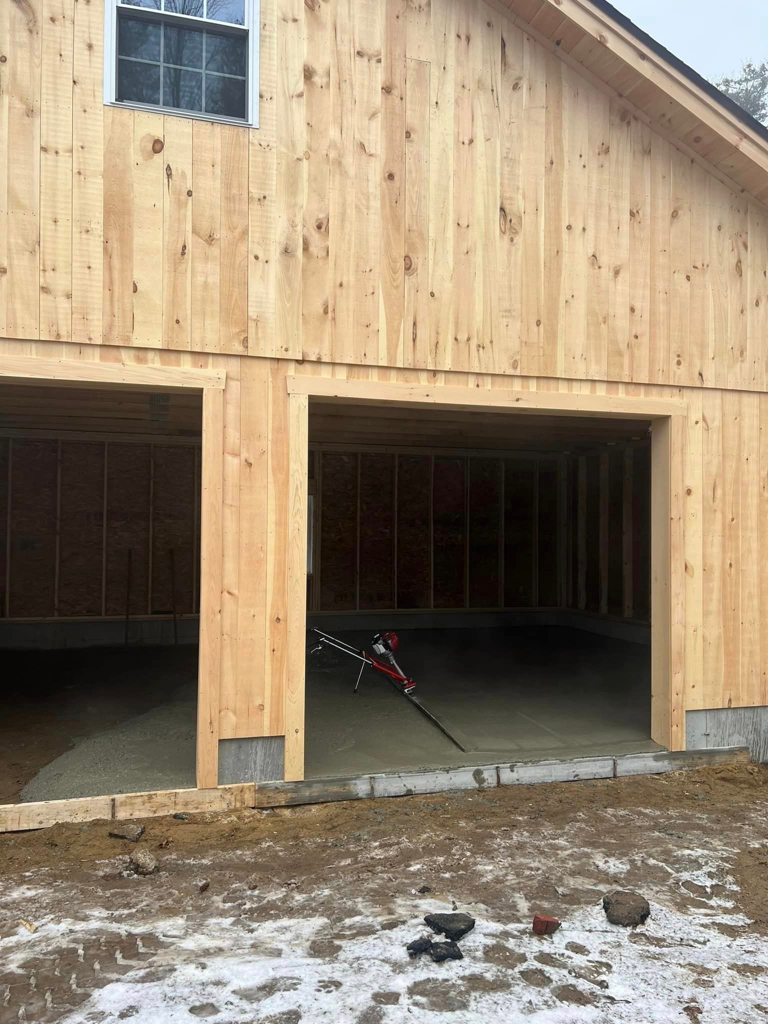 A wooden garage under construction with the doors open.