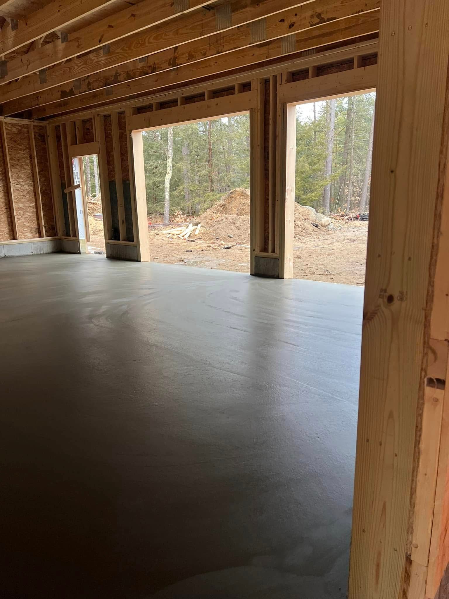 A garage under construction with a concrete floor and wooden beams.