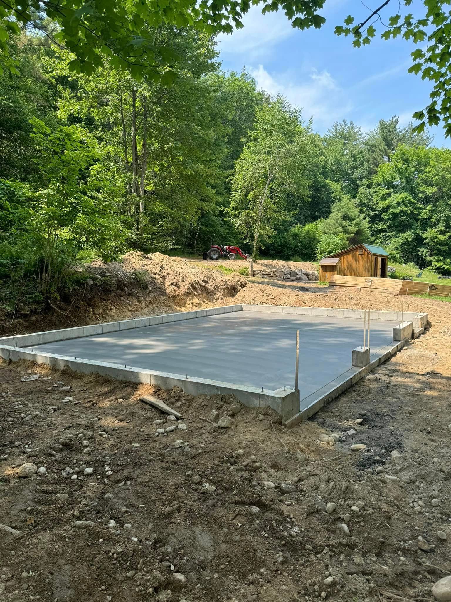 A concrete foundation is being built in the middle of a dirt field.