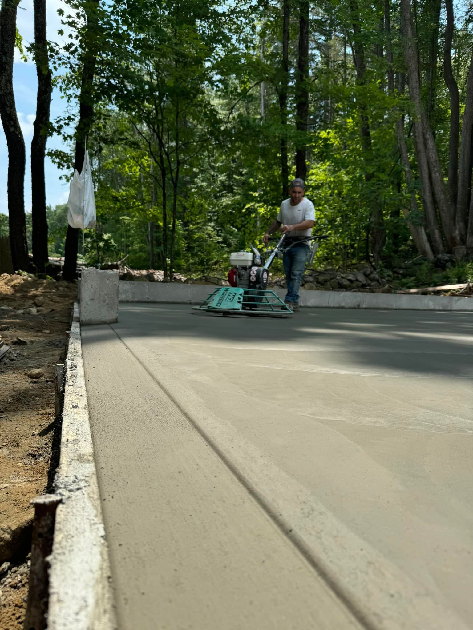 A man is using a machine to level a concrete driveway.