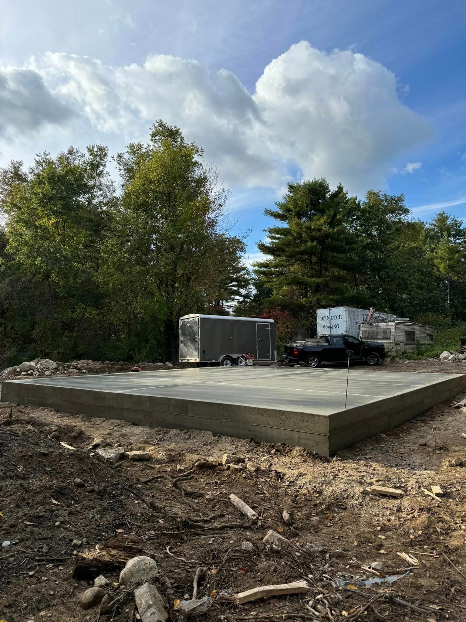 A truck is parked in a dirt lot next to a trailer.