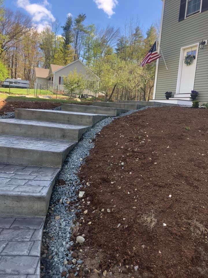 A concrete walkway leading up to a house with a flag in the background.