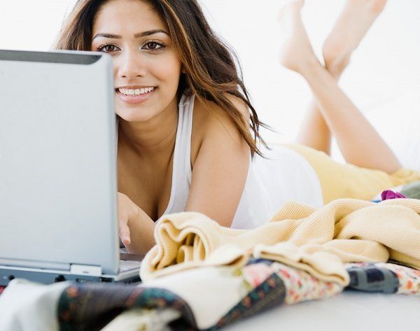 Una donna è sdraiata a pancia in giù e guarda un laptop mentre fa lo speed dating online