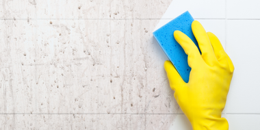 Electrician in yellow hard hat working on wiring inside a wall.