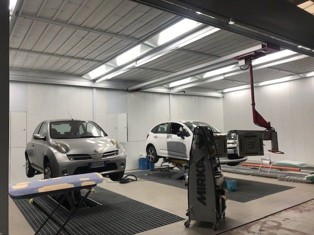 Due auto sui ponti sollevatori in un'autofficina luminosa