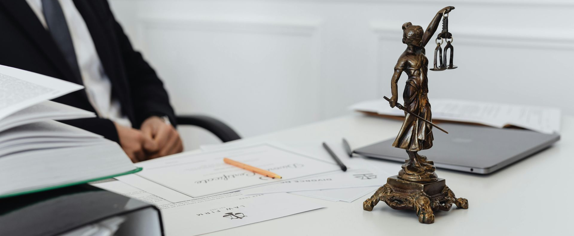 Lawyer’s desk with legal scales, open documents, and a laptop in a bright office