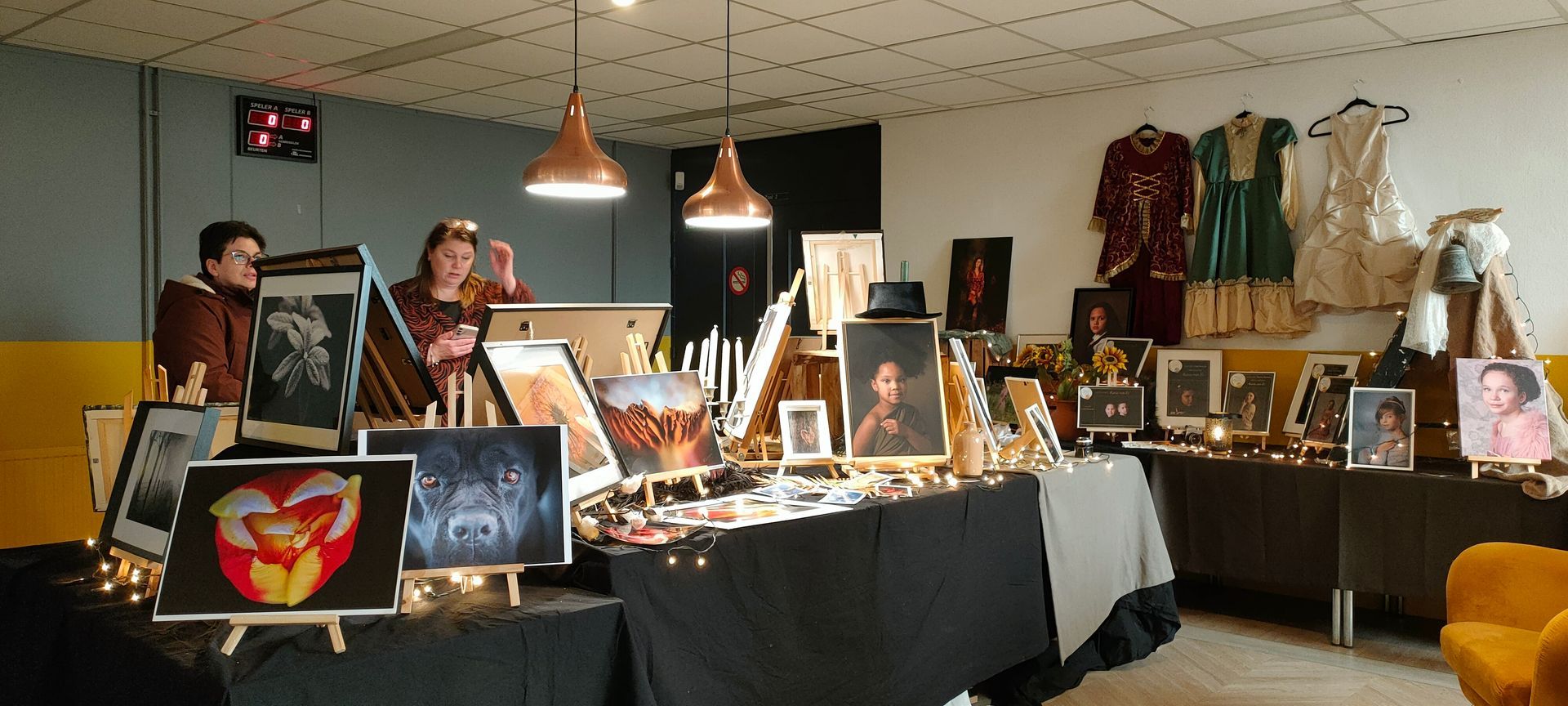 Twee mensen staan rond een tafel met schilderijen erop. Foto popup museum