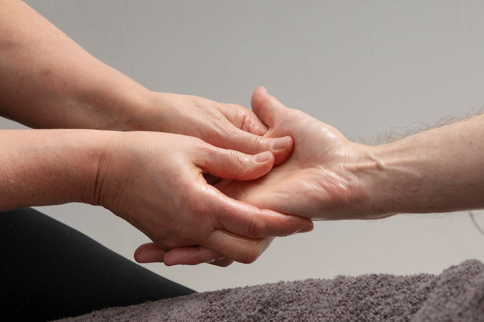 Iemand masseert zachtjes de handpalm van een ander.