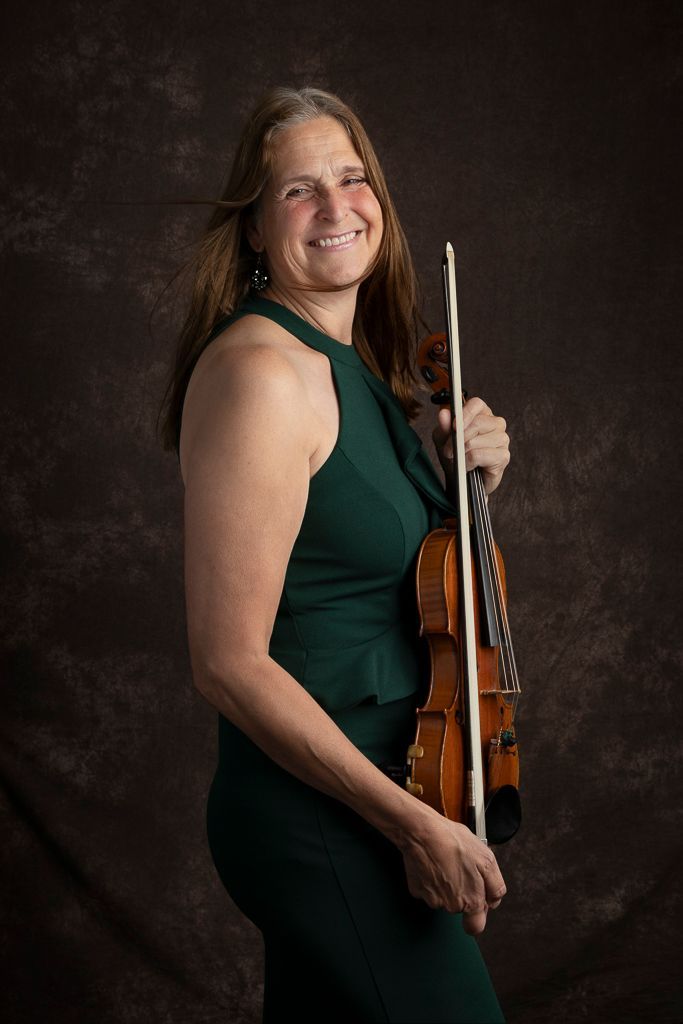 Een vrouw in een groene jurk houdt een viool vast.