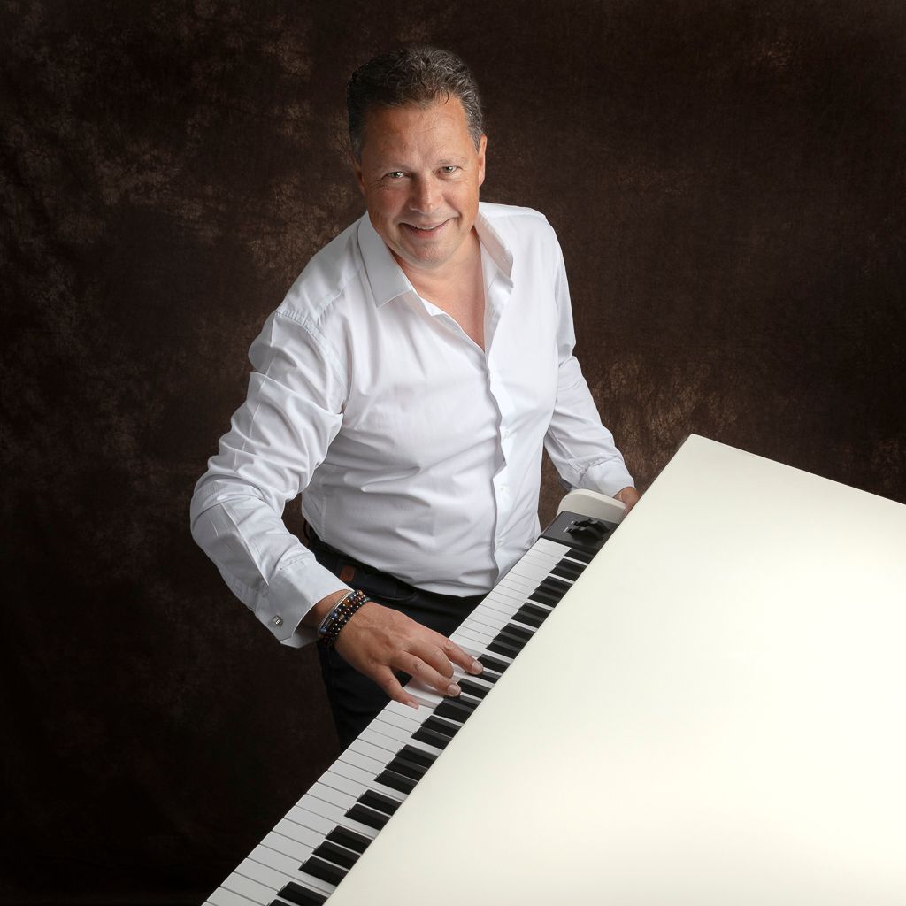 Een man in een wit overhemd speelt op een witte piano