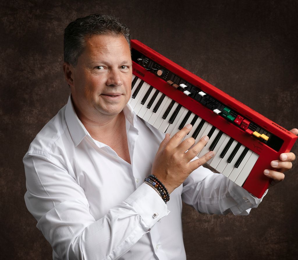 Een man in een wit overhemd houdt een rood toetsenbord vast