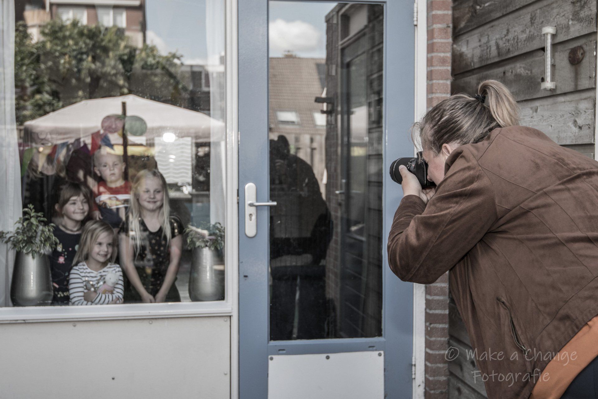 Een vrouw maakt een foto van een familie die achter glas staat