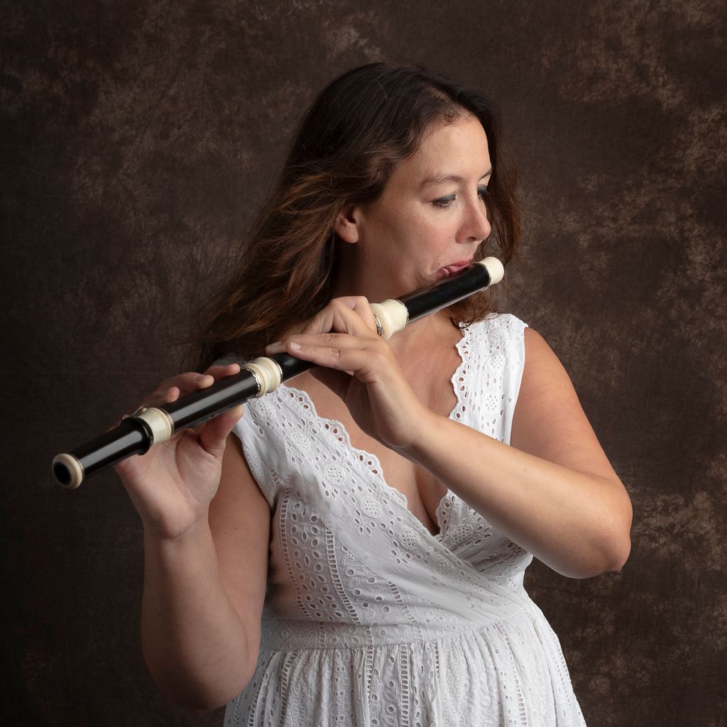 Een vrouw in een witte jurk speelt op een fluit