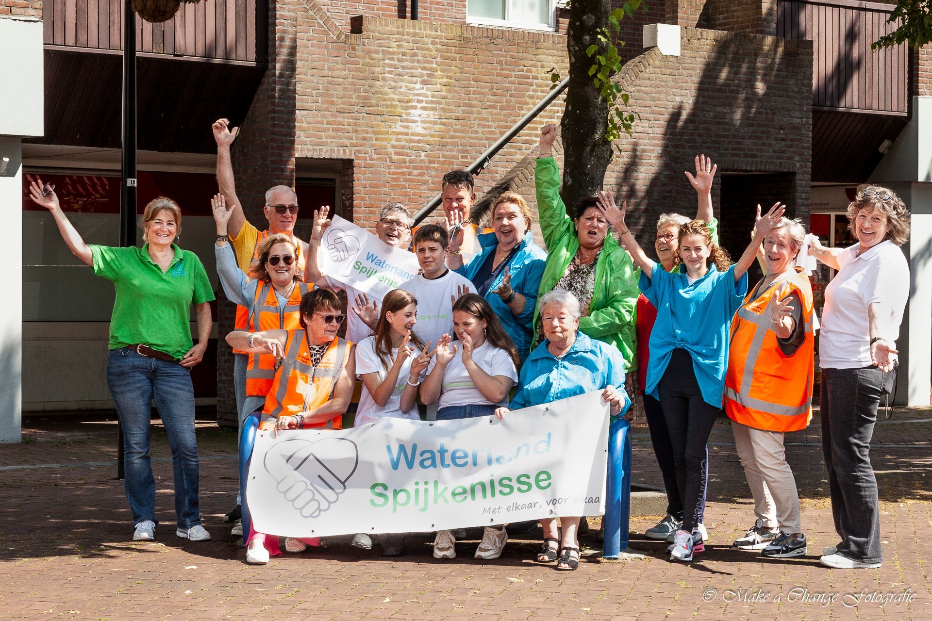 Een groep mensen staat voor een gebouw met een bord met de tekst water.