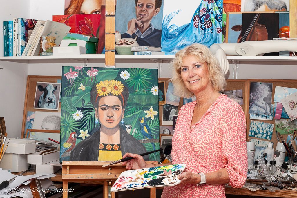 Een vrouw schildert een portret van Frida Kahlo in een atelier.