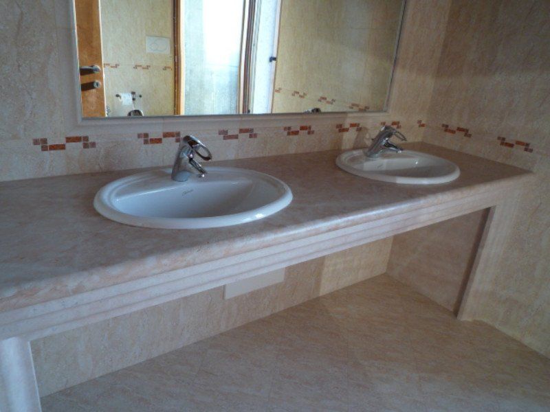 Bagno con due lavabi bianchi ,un grande specchio e pareti,mobile e pavimento marmo bianco e rosa