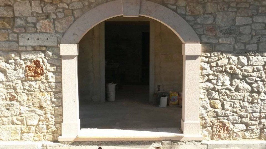 Grande porta di accesso a una casa con arco di mezzo punto realizzata in marmo