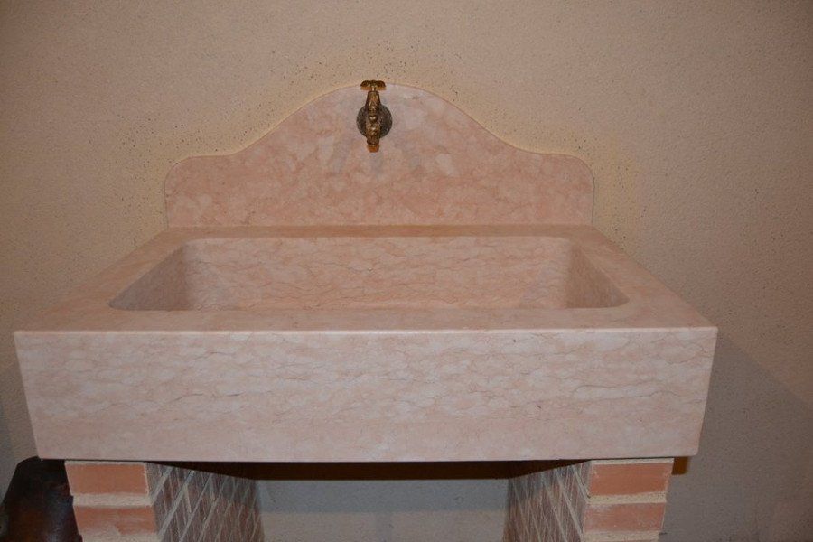 Lavabo di marmo rosa e bianco su due pile di mattoni