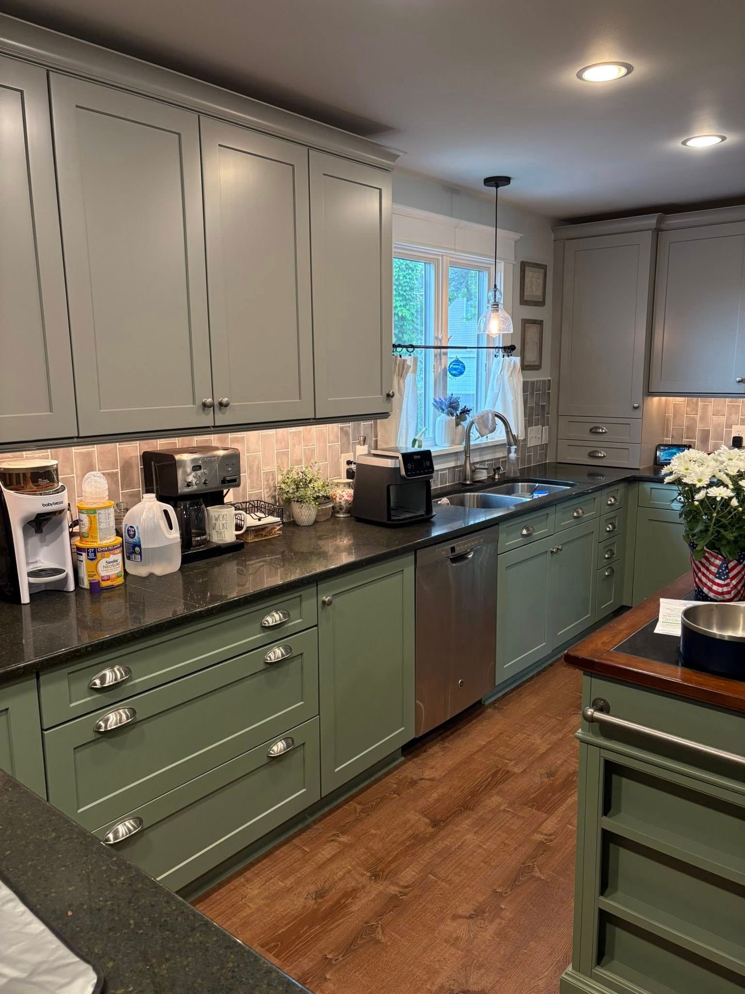 Green kitchen with dark countertops, cabinets, and stainless steel appliances.