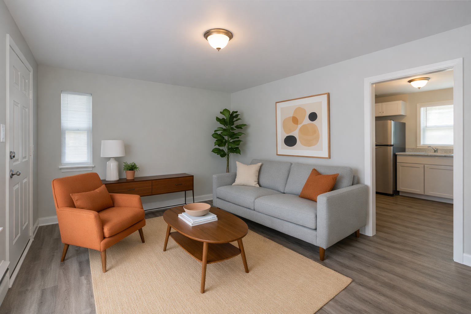 Living room with orange chair, gray sofa, wooden coffee table, and open doorway to a kitchen.