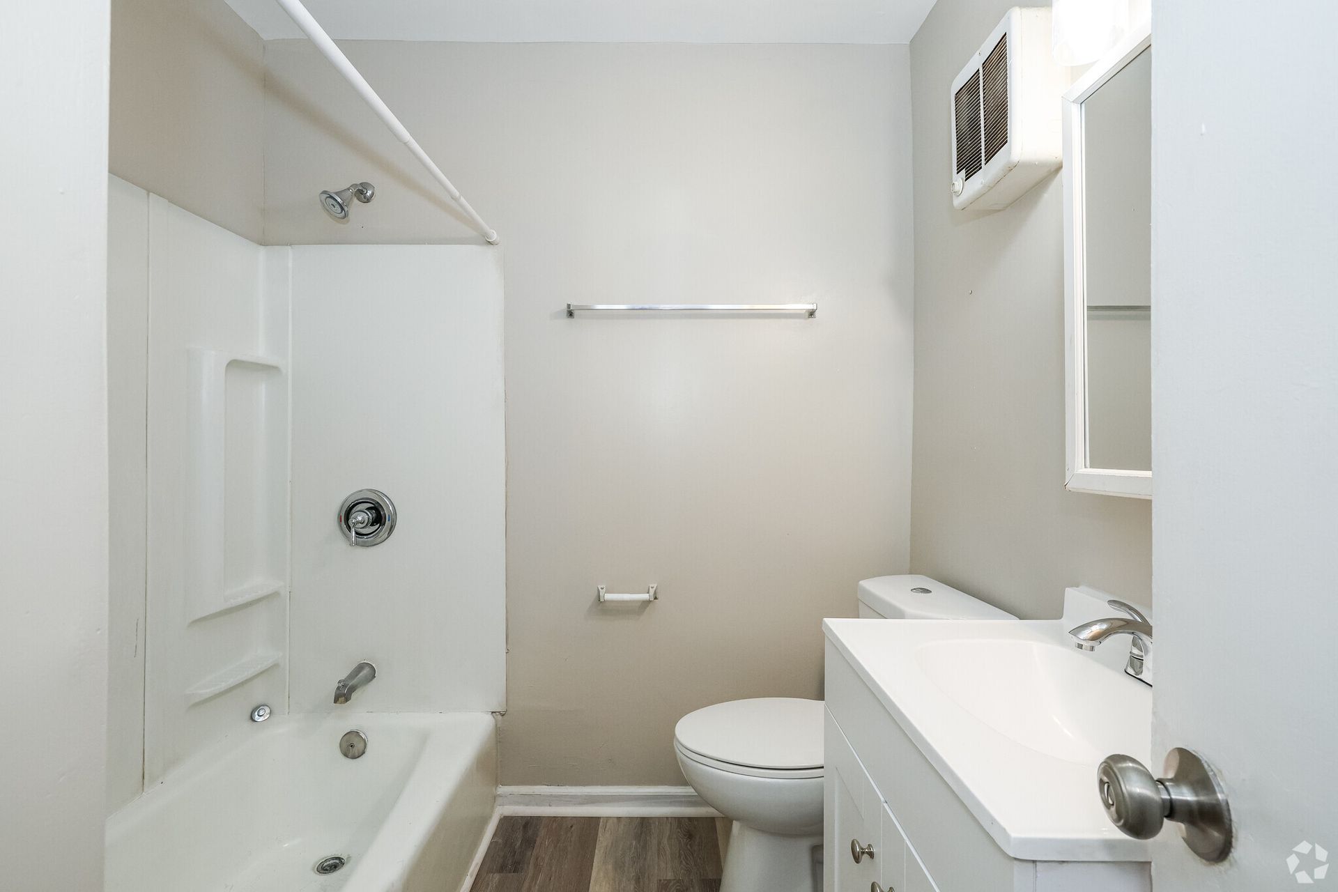 White bathroom with a tub, toilet, and vanity against gray walls.