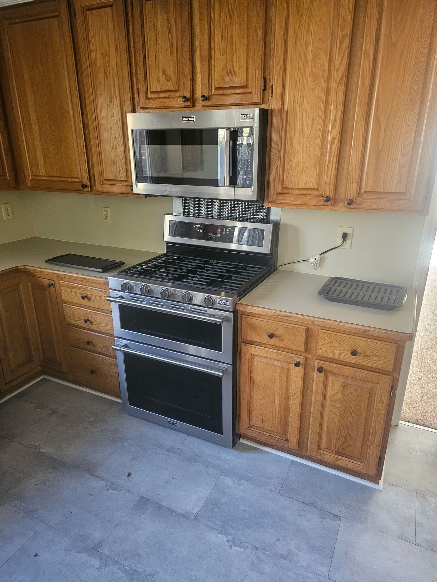 A kitchen area featuring a stainless steel stove and microwave set between honey-colored wooden cabinets.