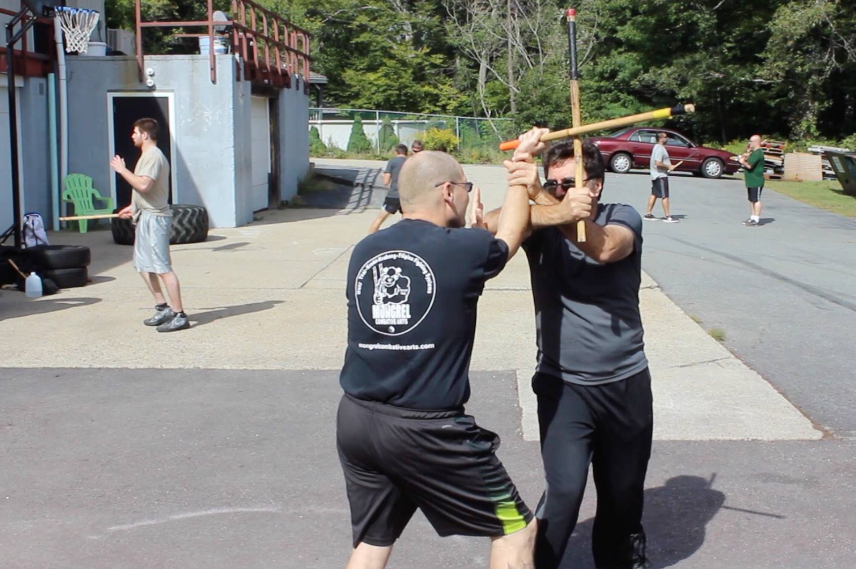 two men are practicing martial arts in a parking lot