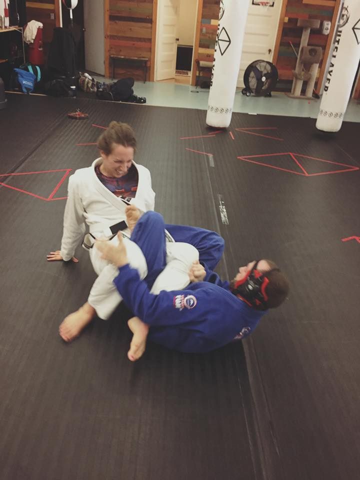 two people are wrestling on a mat in a gym .