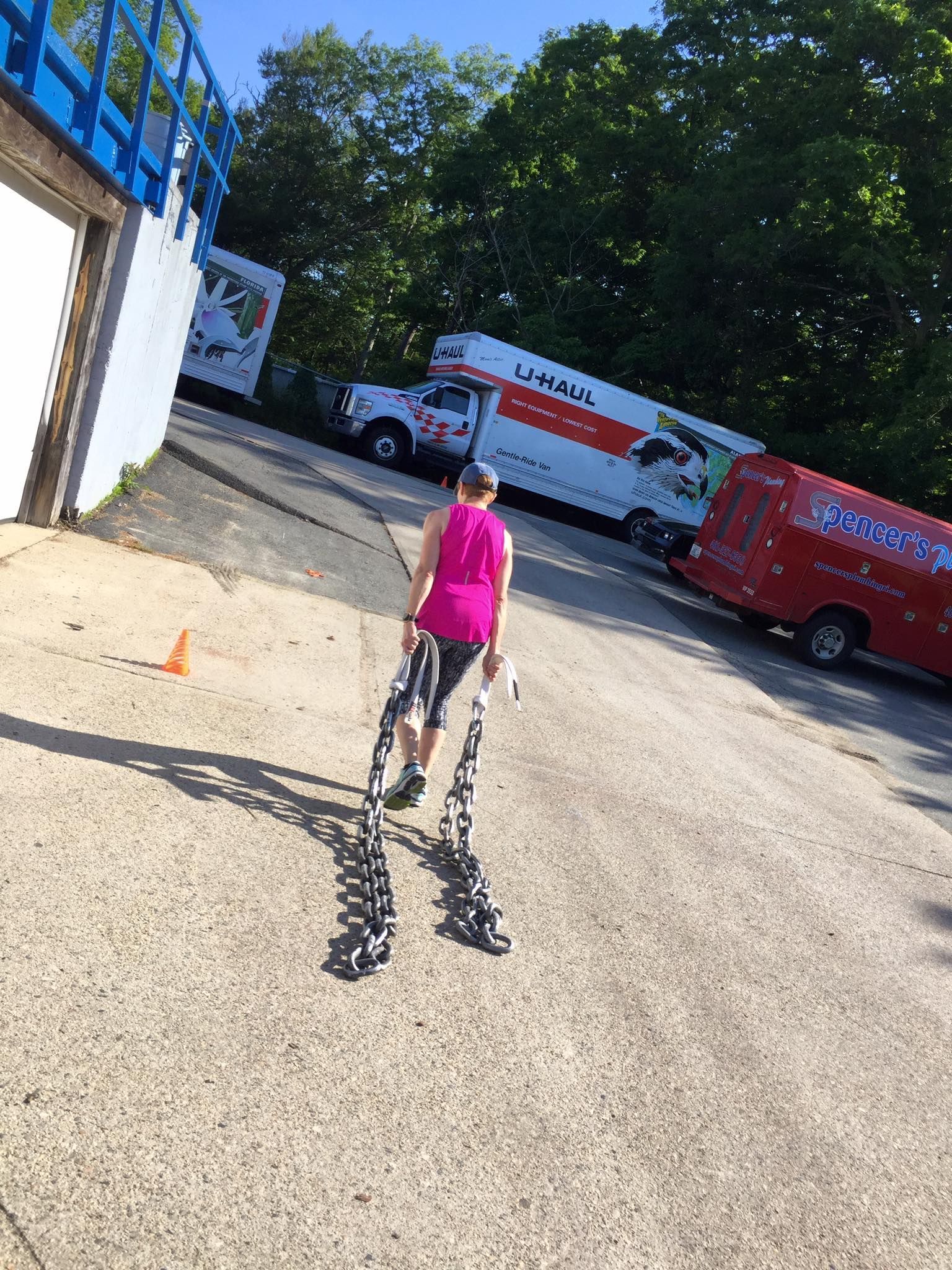 a woman is walking down a road next to a moving truck .