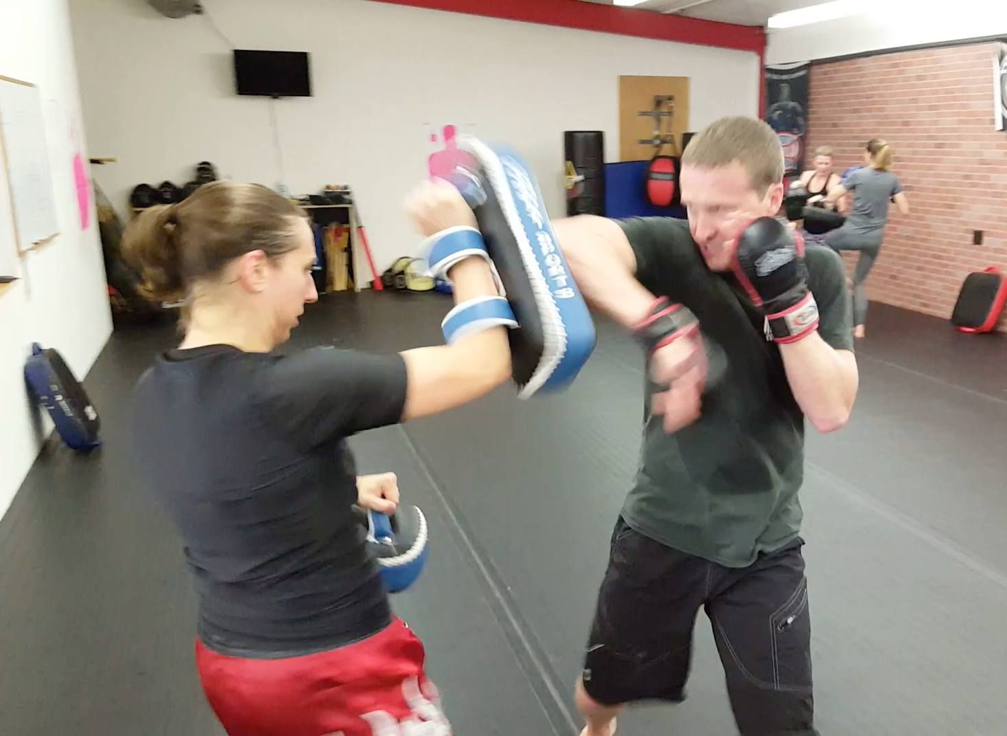 a man and a woman are practicing martial arts in a gym