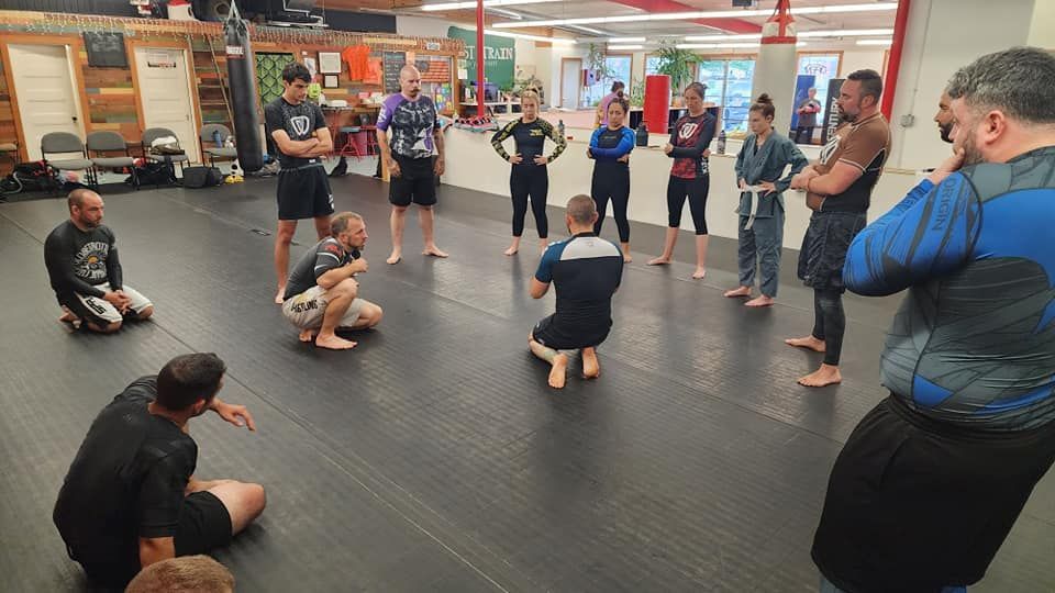 a group of people are standing in a circle on a mat in a gym .