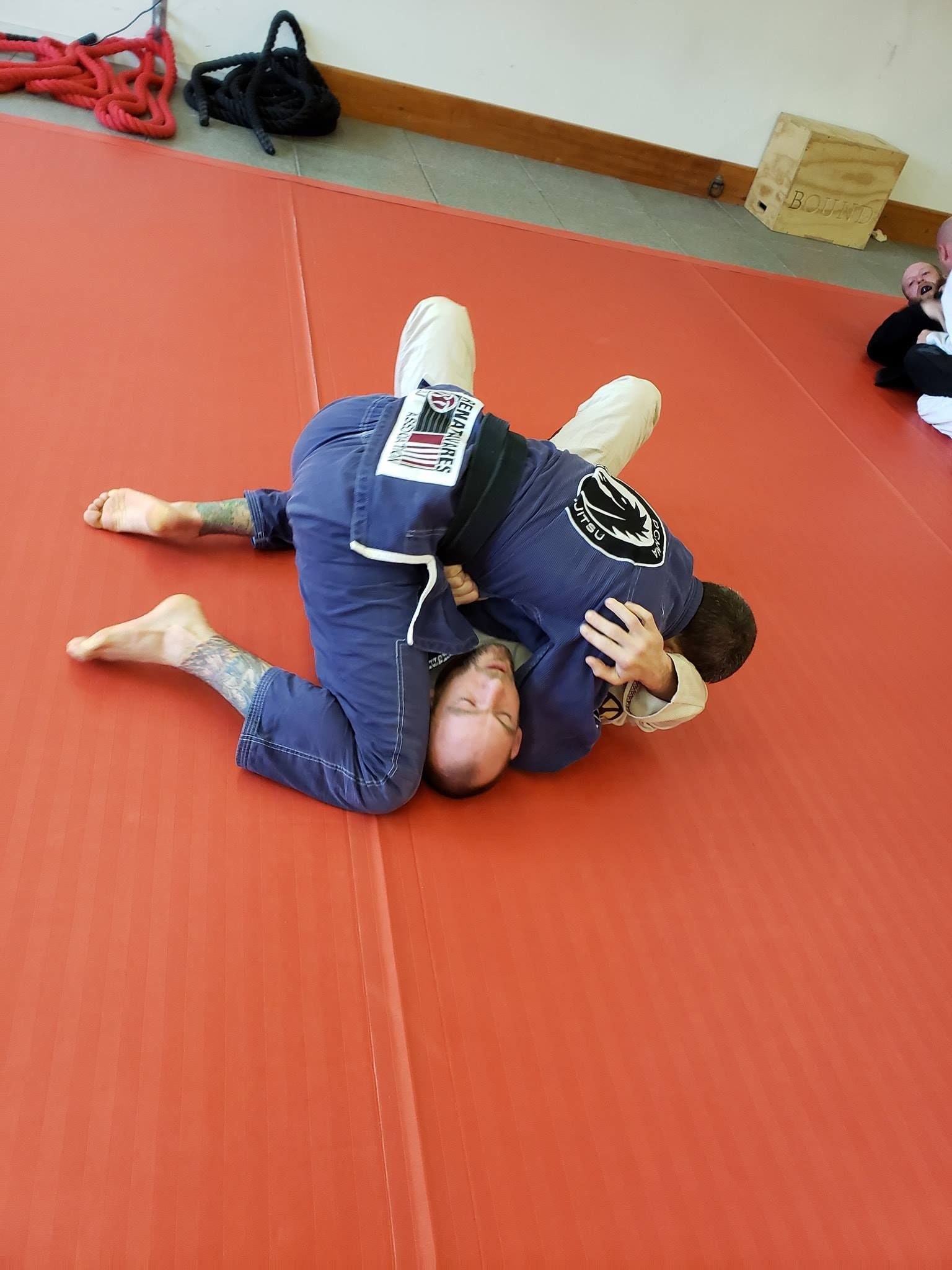 two men are wrestling on a red mat .