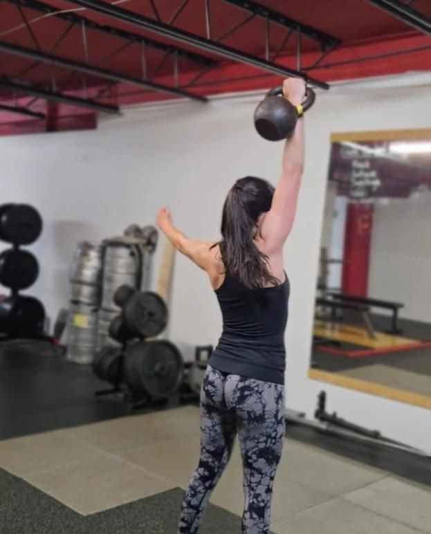 a woman is squatting on a wooden box in a gym .
