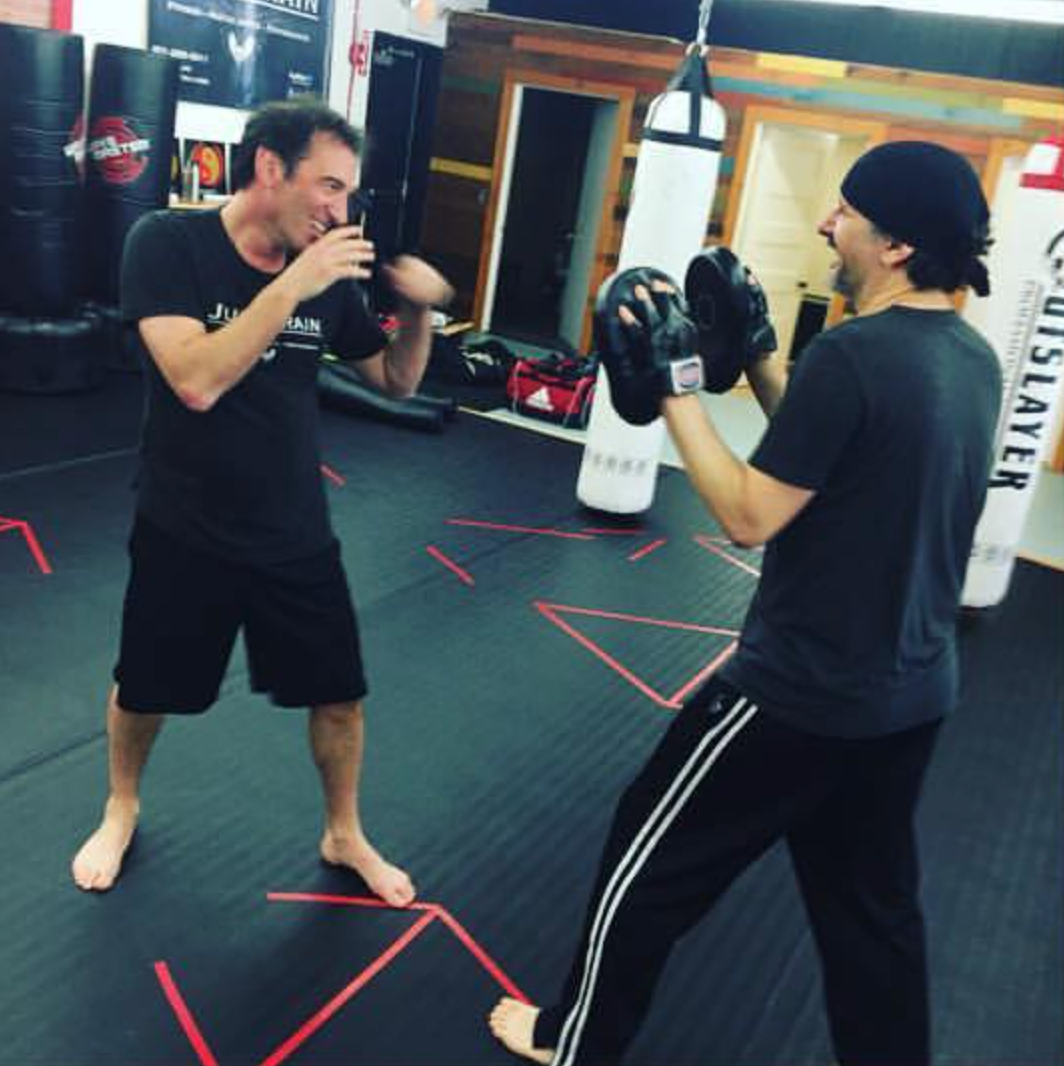 two men are boxing in a gym with a sign that says outslayer