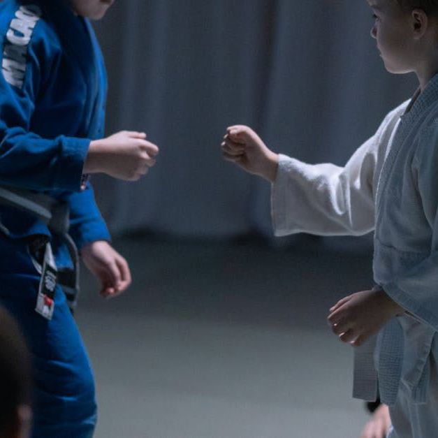 two young boys in karate uniforms are standing next to each other in a dark room .
