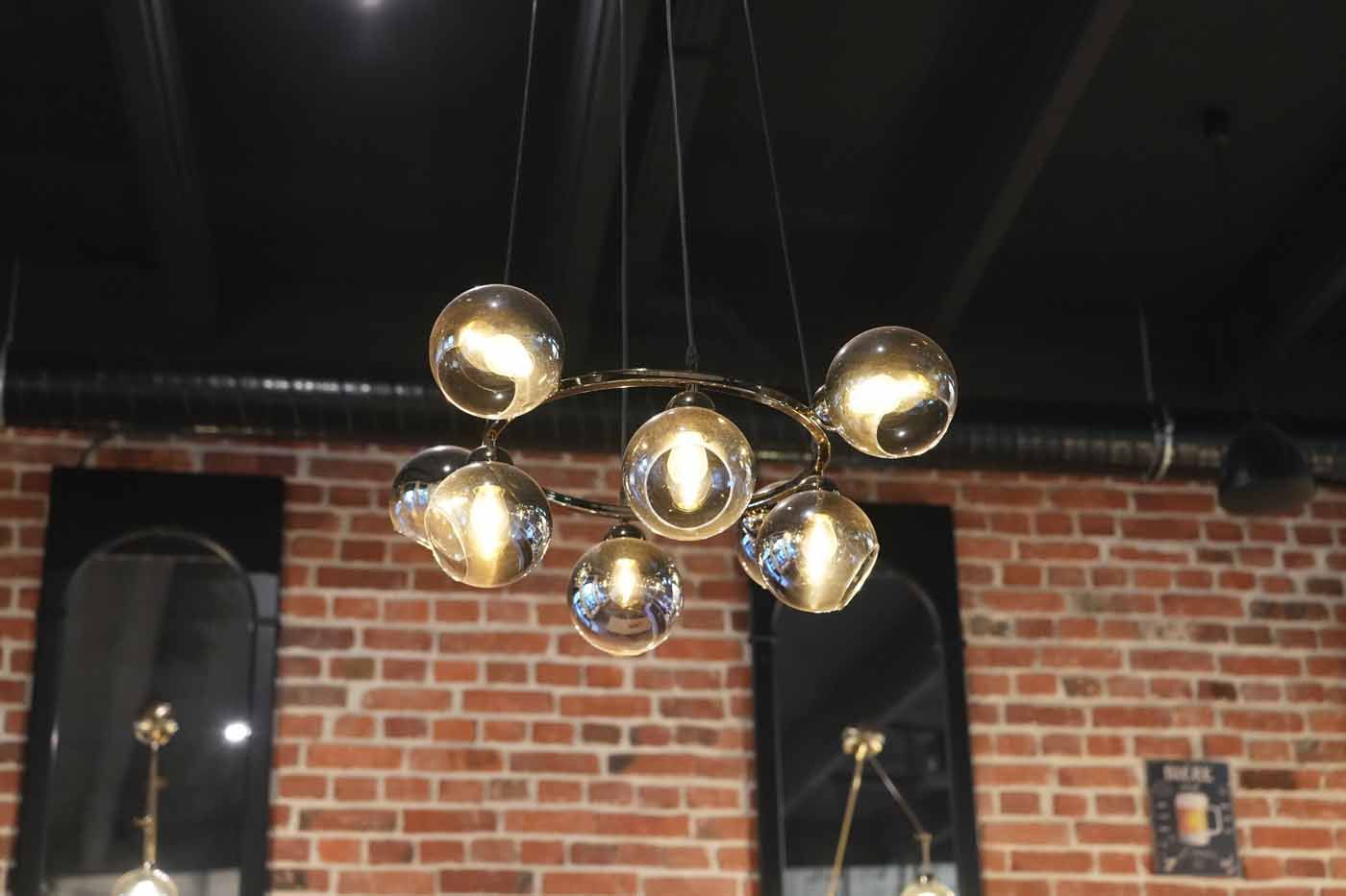 A chandelier is hanging from the ceiling in a room with a brick wall.