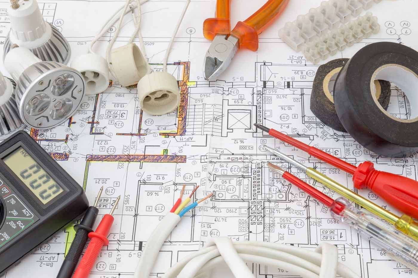 An electrician 's tools are laid out on top of a blueprint