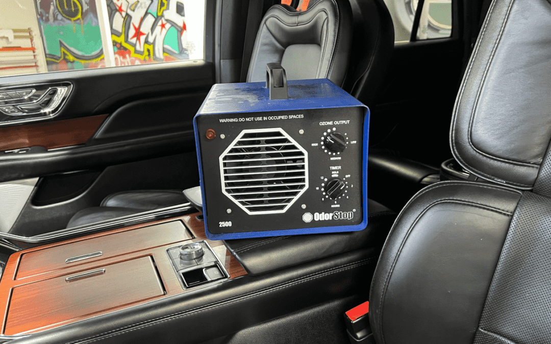 Blue ozone generator sits inside a car on the center console. Black leather seats and wood trim are visible.