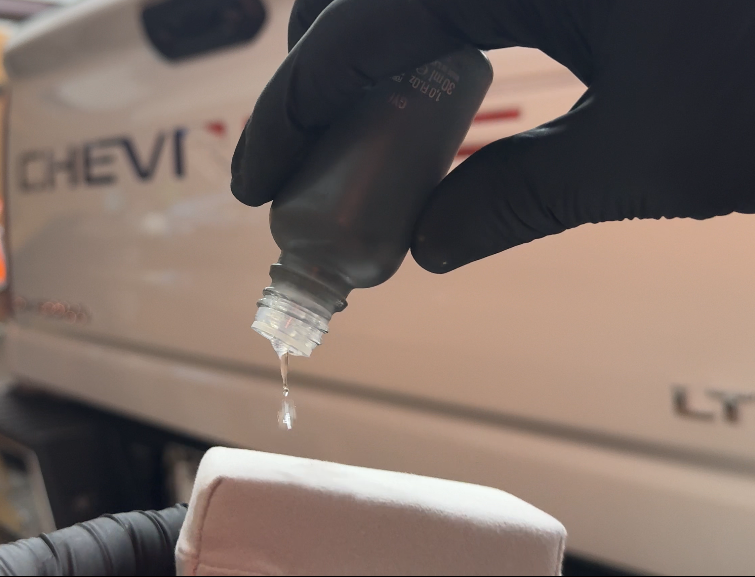 Pouring ceramic coating from a bottle onto an applicator pad. Preparing to do a 1 step ceramic coating application.