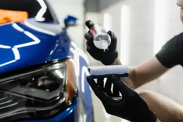Luxline employee prepping a car with iron remover spray before applying a ceramic coating.