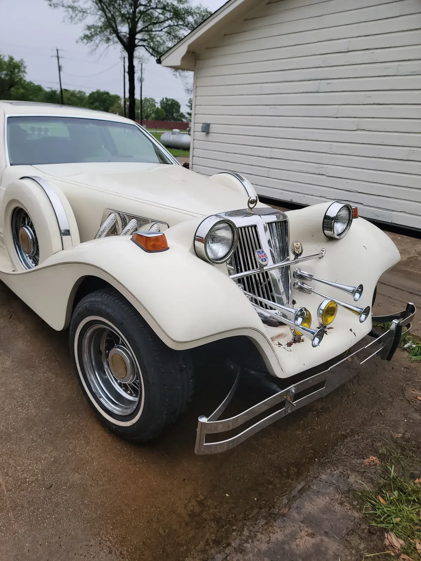 CMC Classic Tiffany Coupe with chrome details parked outside a white building, freshly detailed.