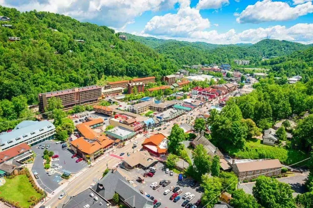 Aerial view of a town nestled in a lush, green mountain valley with hotels, shops, and roads winding through the center.