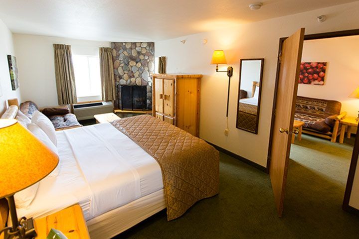 Bedroom with bed, fireplace, wooden wardrobe, and open doorway to another room with seating.
