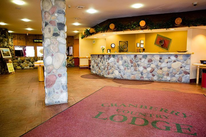 Lobby of Cranberry Country Lodge with stone accents, red welcome mat, and reception desk.