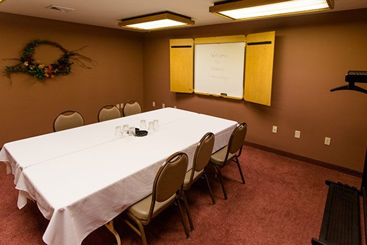 Conference room with a rectangular table, chairs, and a whiteboard.