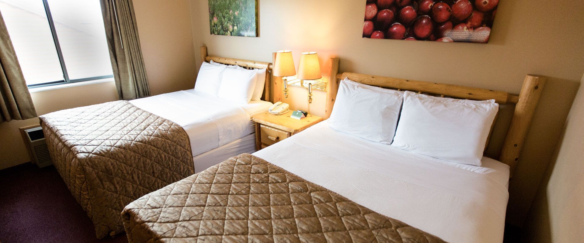 A hotel room with two beds, two lamps, and a window.