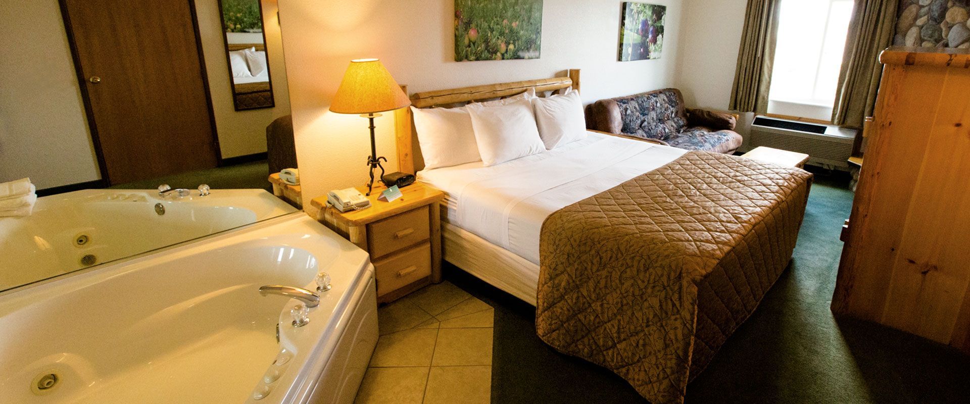Hotel room with a king-sized bed, a jacuzzi tub, a sofa, and rustic wood furniture.