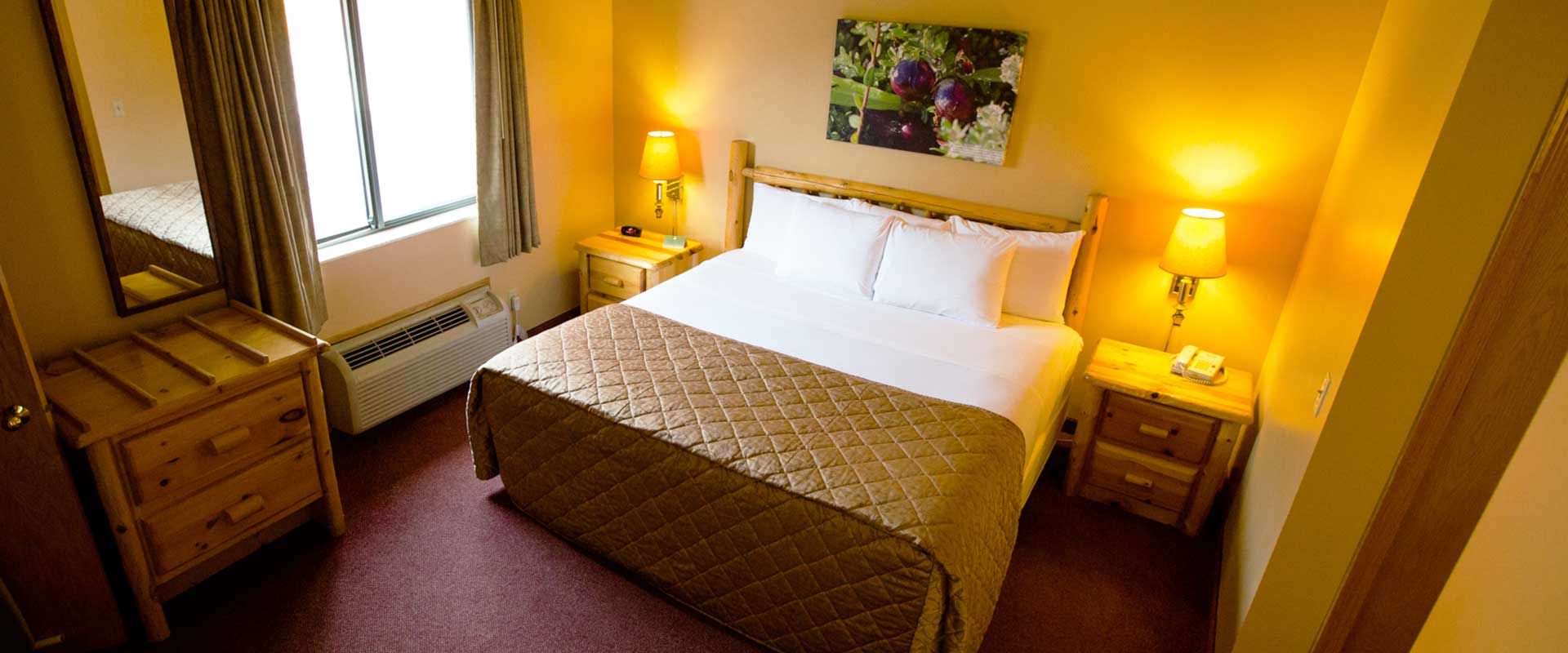 Bedroom with a bed, two nightstands with lamps, a window, and a dresser.