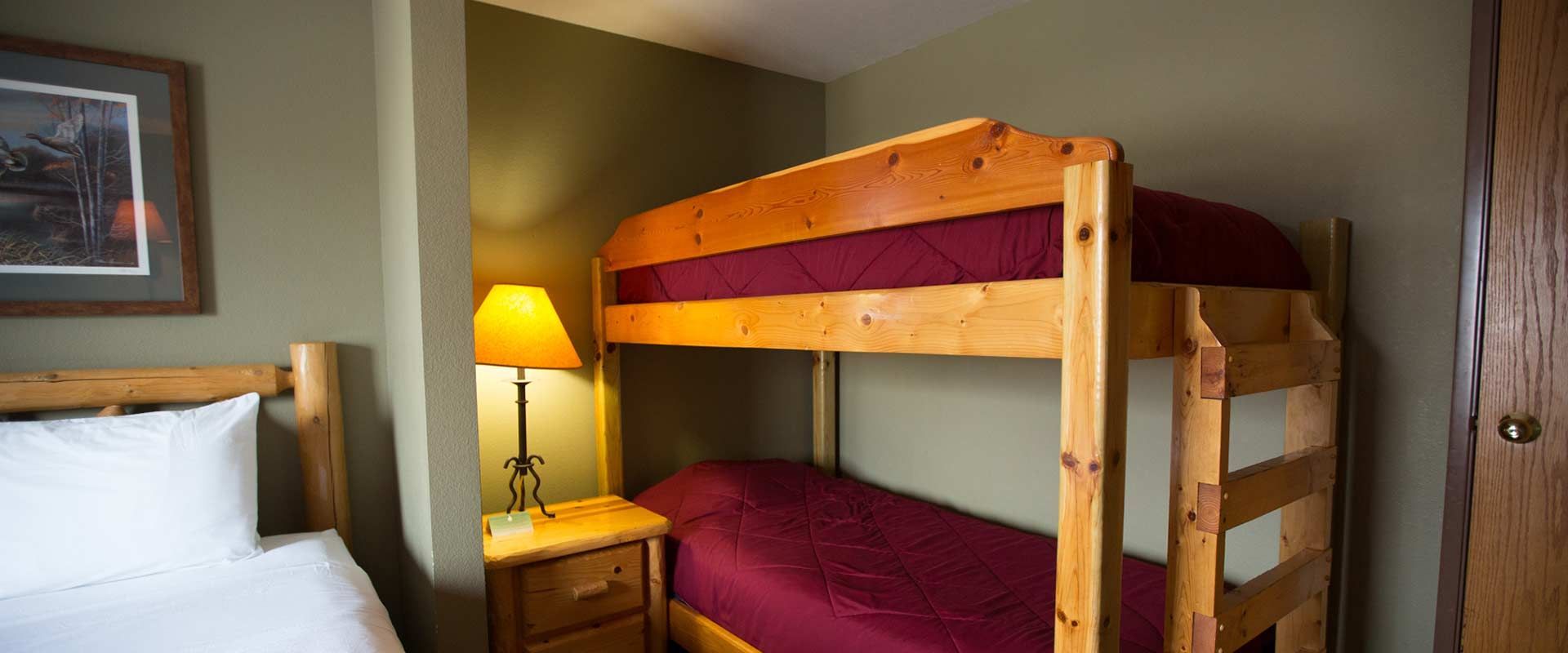 A room with bunk beds, a single bed, a nightstand, and a framed picture.