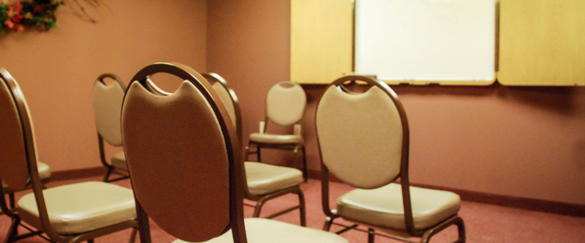 A circle of chairs in a room with a whiteboard, likely a meeting or therapy setting.
